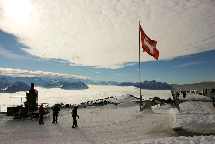 A snowy landscape with a flag, a train, and mountains in the background. 5