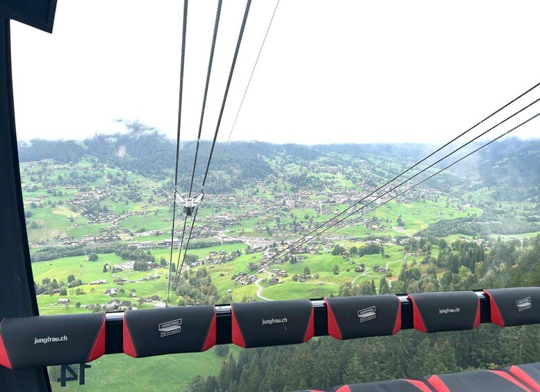 A cable car with a scenic view of a green valley and scattered houses. 4