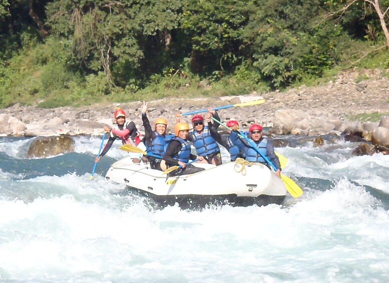 A group of people in a raft navigating a river with rapids. 1