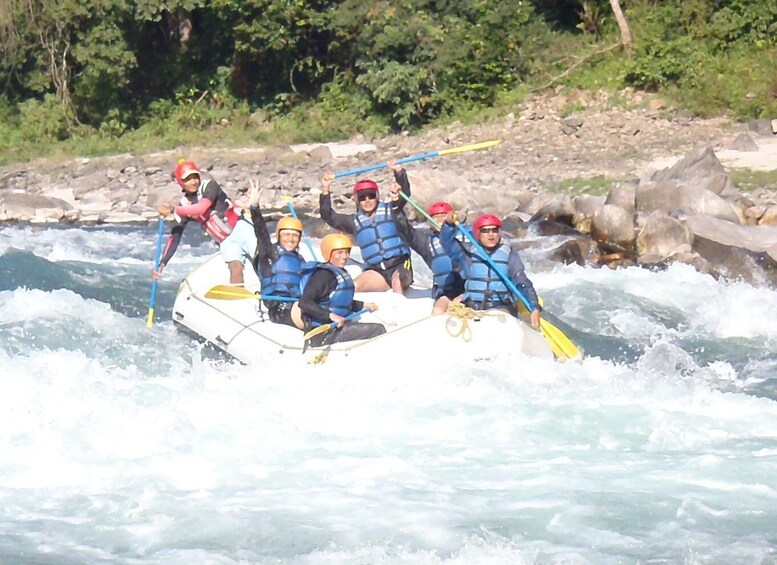 A group of people in a white raft navigating a river with rapids. 3