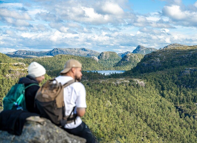 Two hikers on a mountain overlooking a valley with a lake and forested mountains. 4