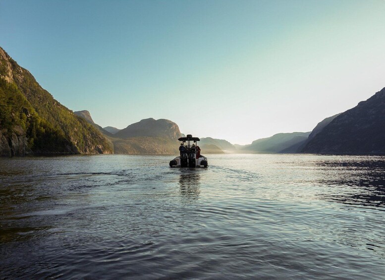 A boat on a calm river surrounded by steep, forested hills. 2