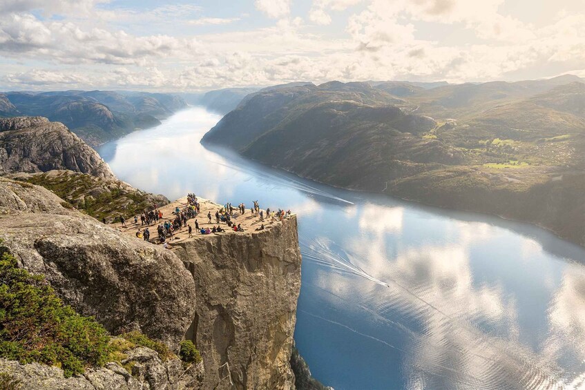 A cliff overlooking a calm lake with people gathered at the edge. 1