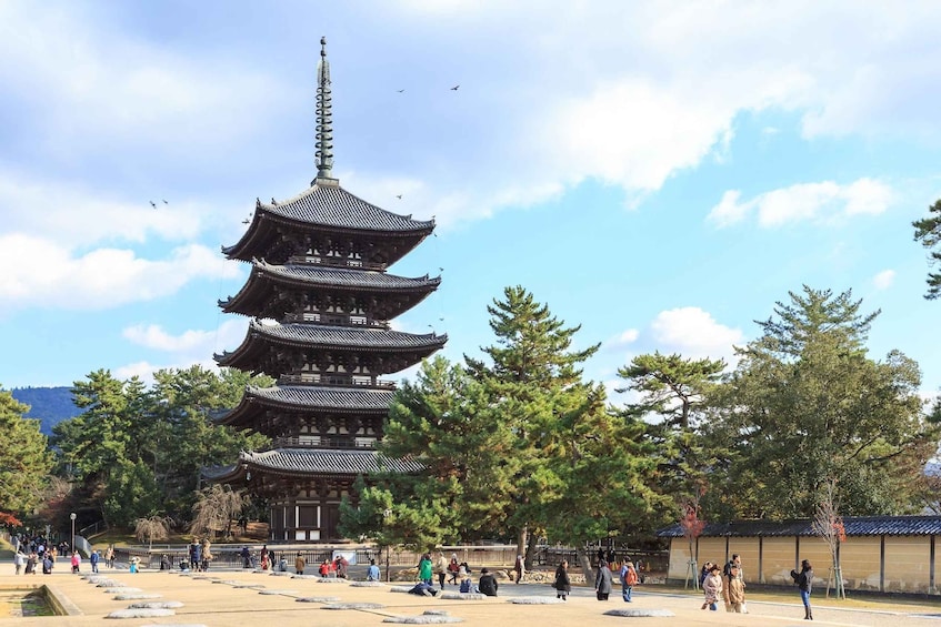 A traditional multi-tiered pagoda surrounded by a park with visitors. 5