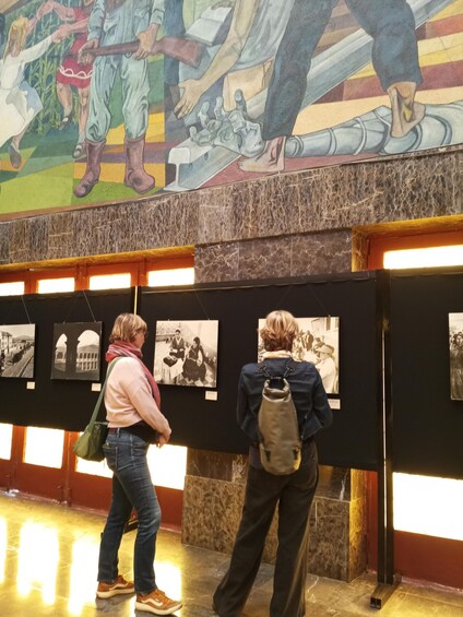 A museum with a large mural and several framed photographs on display. 5