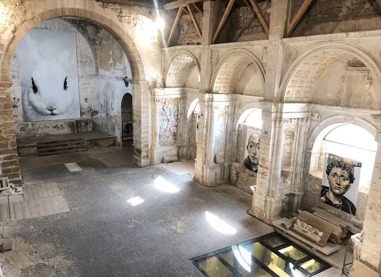 An ancient stone structure with arched doorways and a large mural. 2