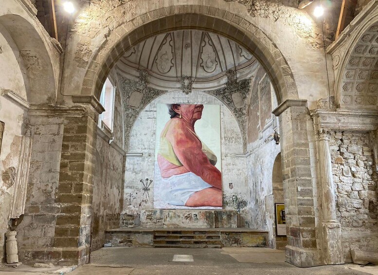 An interior with a large mural, stone arches, and a vaulted ceiling. 3