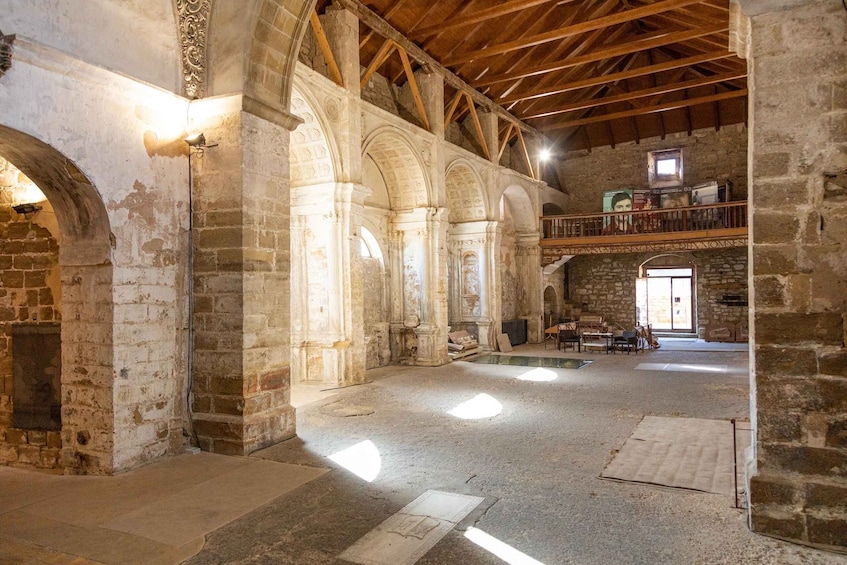 An interior with stone arches, wooden beams, and a balcony with books. 4
