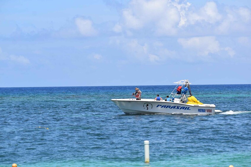 A white boat named 'Patria y Vida' with 'PARASAIL' written on it, moving on a calm sea. 3