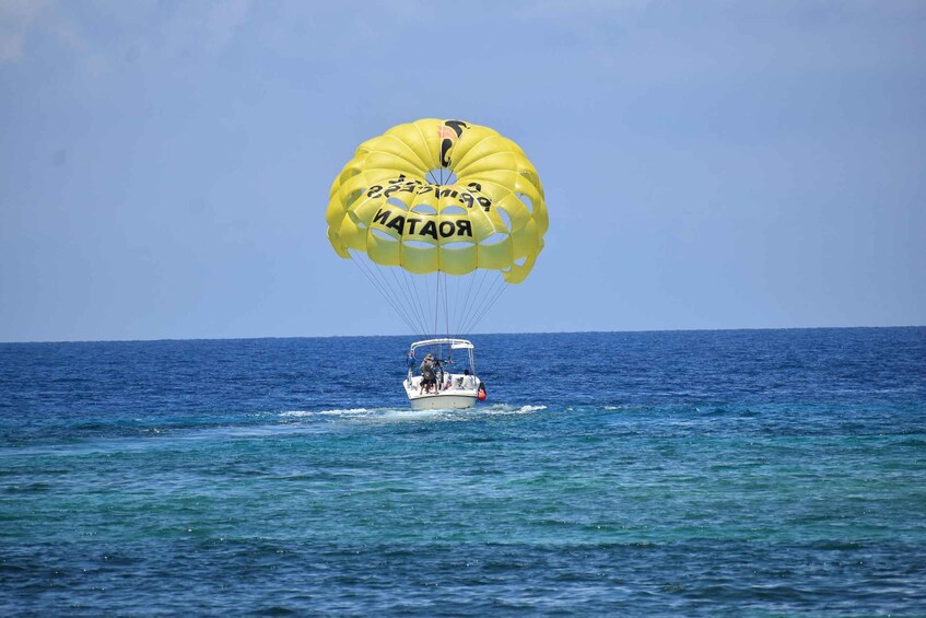 A parasailing activity with a yellow canopy over a boat on the ocean. 4