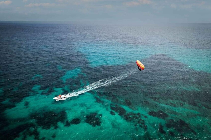 A parasail over turquoise waters with a boat creating a wake. 5