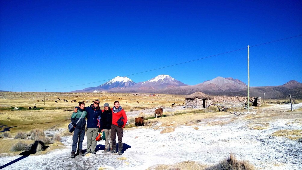 A group of people standing in a dry, grassy field with mountains in the background. 3