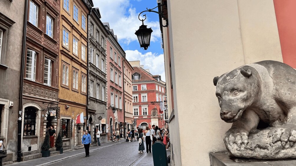 A cobblestone street lined with historic buildings, a street lamp, and a stone lion statue. 4