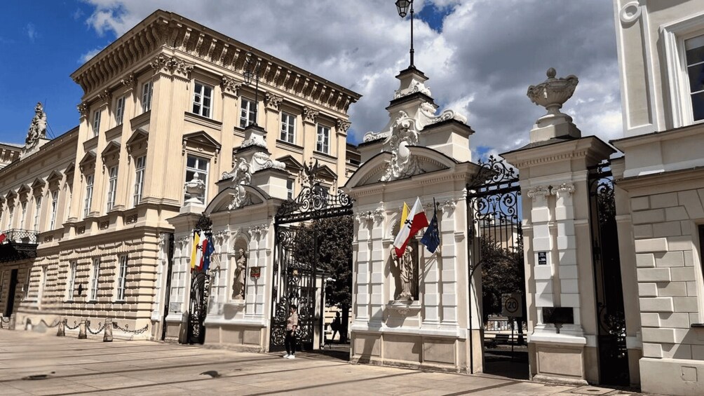 A historic building with ornate architecture, a gated entrance, and flags. 5