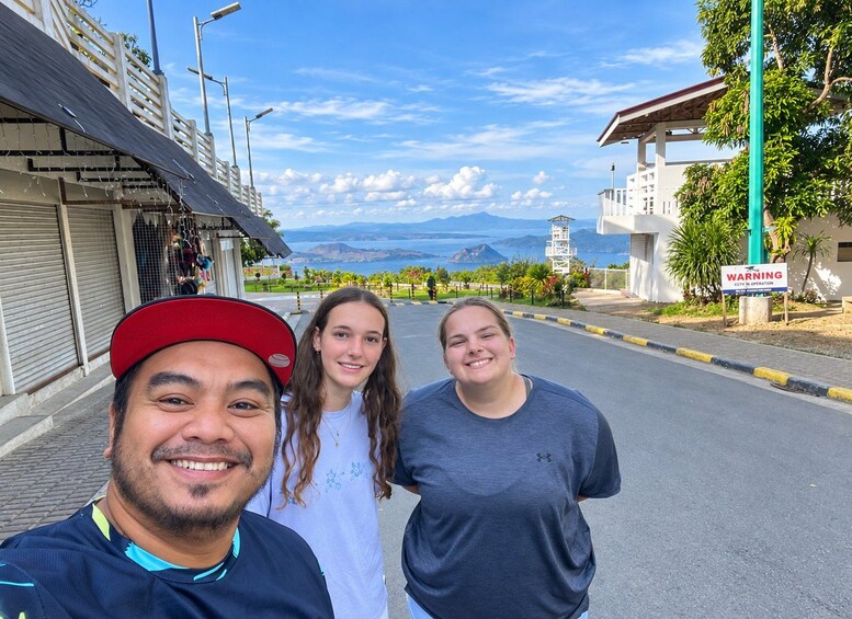 Trois personnes se tiennent sur une rue, avec une vue sur les montagnes et un panneau d’avertissement. 4