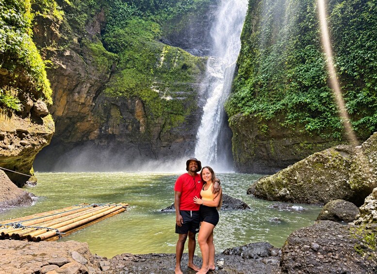 Une cascade, un terrain rocheux et un couple se tenant près d’une rivière. 3
