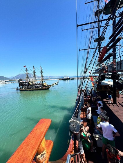 A wooden pier with people on a boat and another ship in the background. 3