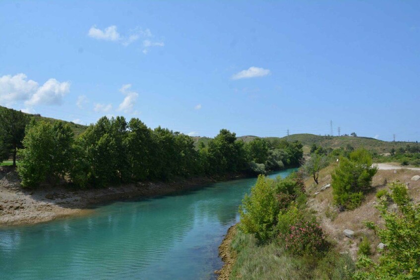 A river winding through a hilly landscape with dense green foliage and a clear blue sky. 2