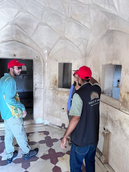 Three people in a historical building with arched ceilings and tiled floors. 3