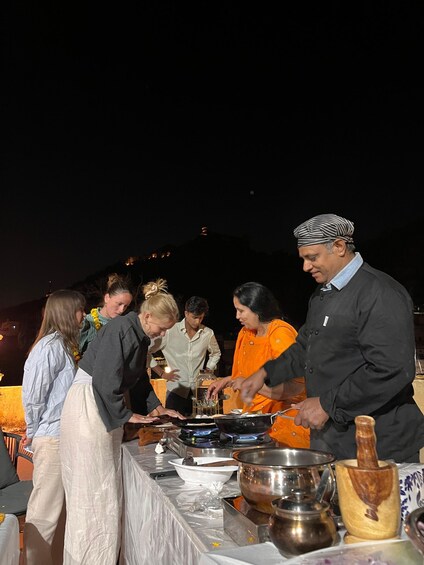 A group of people preparing food outdoors at night with a table set up for cooking. 4