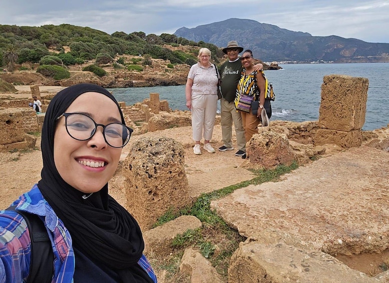 A historical site with ruins and a body of water in the background. 1