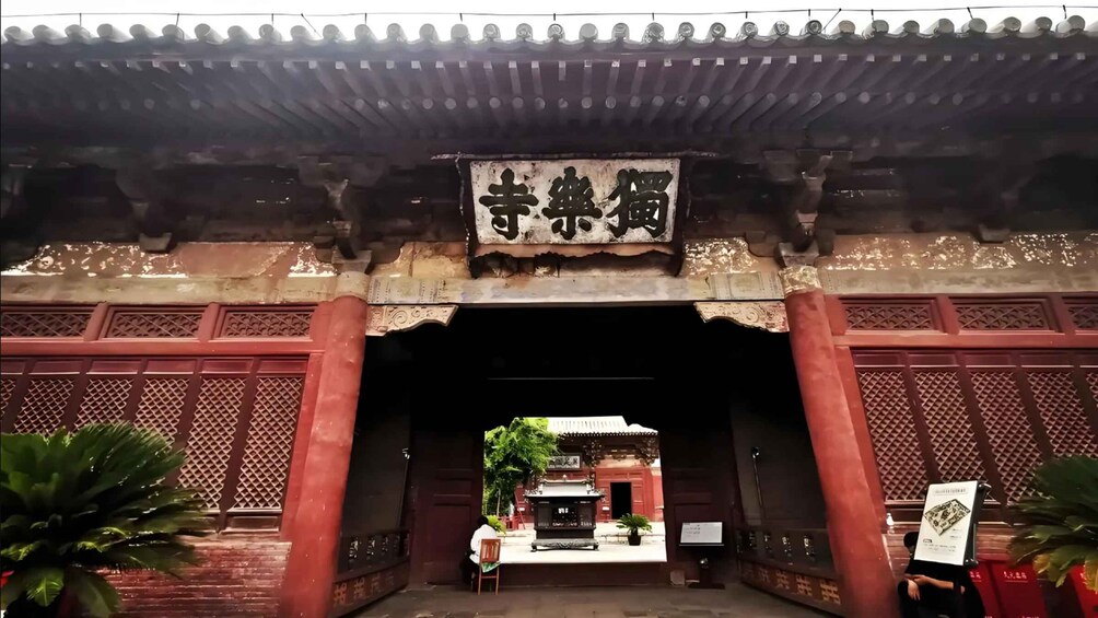 A traditional Chinese gate with intricate carvings and a sign above it. 5