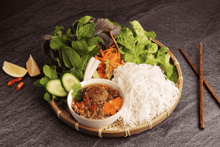 A bowl of soup with meat, vegetables, and noodles on a dark surface. 5