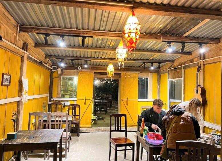 An indoor dining area with wooden walls and tables, a guitar hanging on the wall, and a person serving food. 4