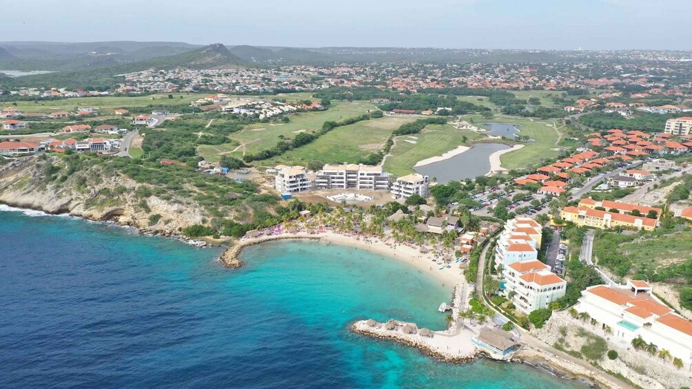 A coastal town with a beach, residential buildings, and a golf course. 3