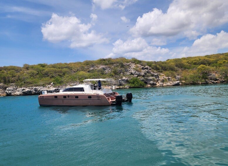 A boat named 'Exact' anchored near rocky shores with clear blue water. 1