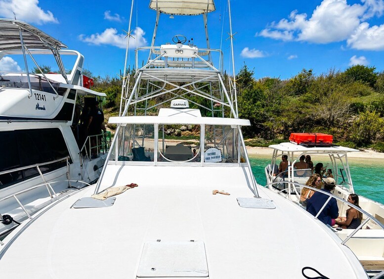 A boat with a white deck, a steering wheel, and a Garmin navigation device. There are people on the boat and another boat in the background. 4