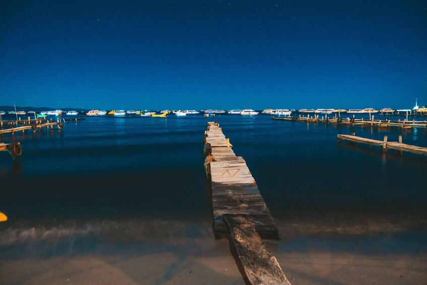 A pier extending into calm water with boats docked at the pier's end. 1