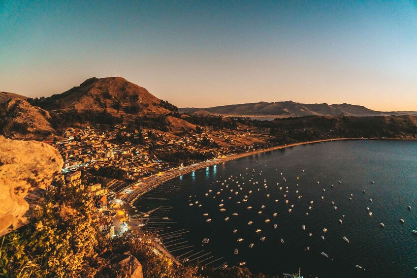 A coastal town with a marina filled with boats, surrounded by hills and a clear sky. 3