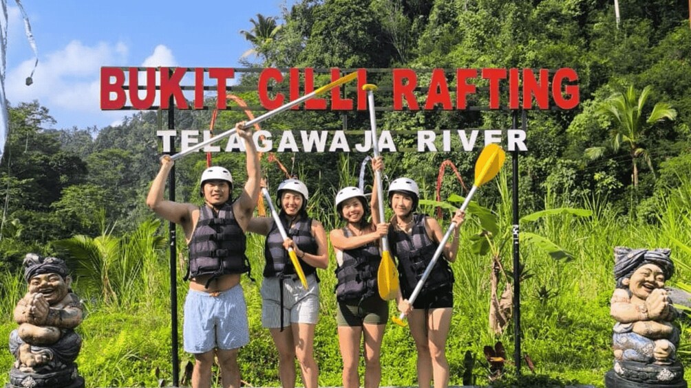 A group of people rafting on the Telaga Waja River, with a sign reading 'BUKIT CILI RAFTING'. 1