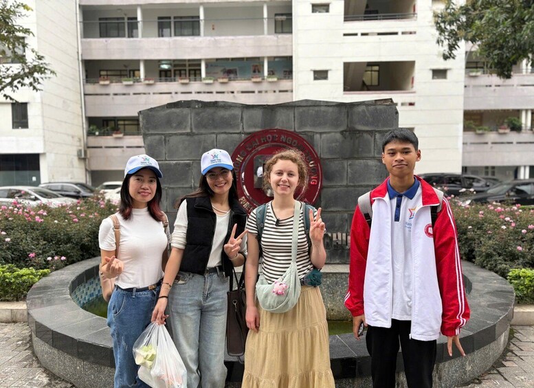 Four people standing in front of a building with a circular emblem. 2
