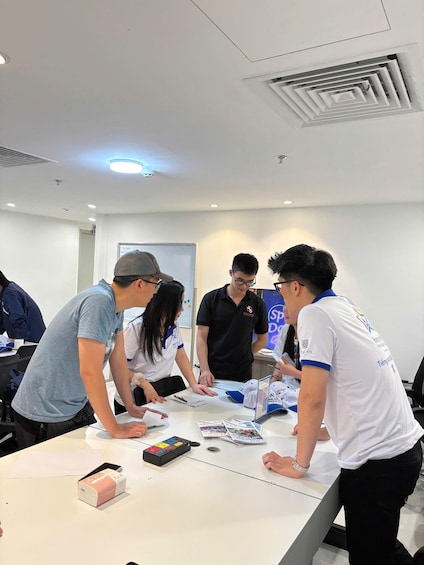 A group of people at a table with a whiteboard, papers, and a box of tissues. 3