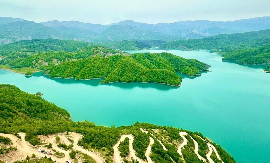 A mountainous landscape with winding roads and a turquoise lake. 1