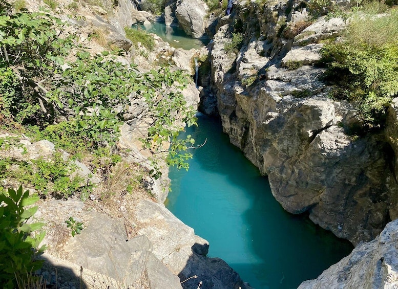 A narrow canyon with a turquoise river, rocky cliffs, and sparse vegetation. 2