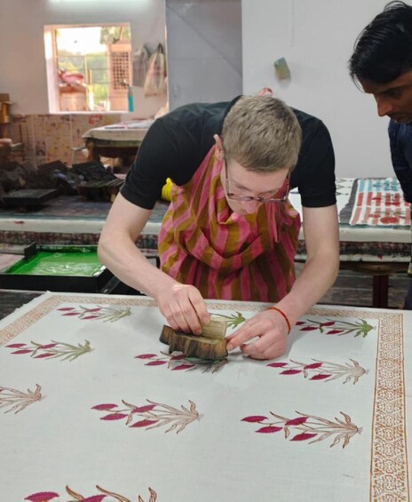A person working on a table with a patterned tablecloth, surrounded by various tools and materials. 4