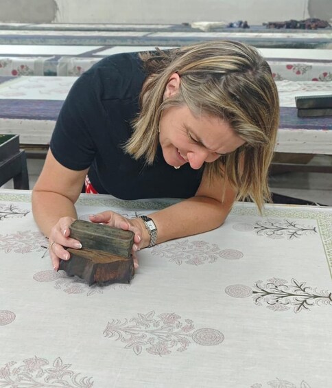 A person working on a wooden box with floral patterns on a table. 2