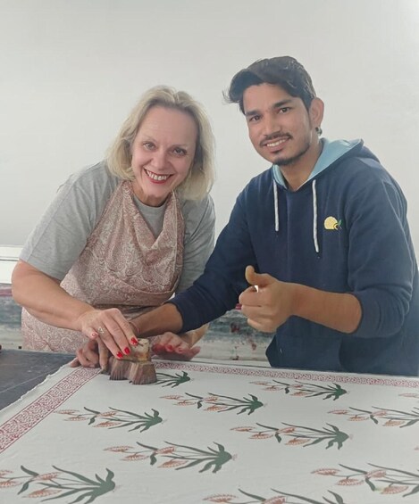 Two people sitting at a table with a patterned tablecloth. 3