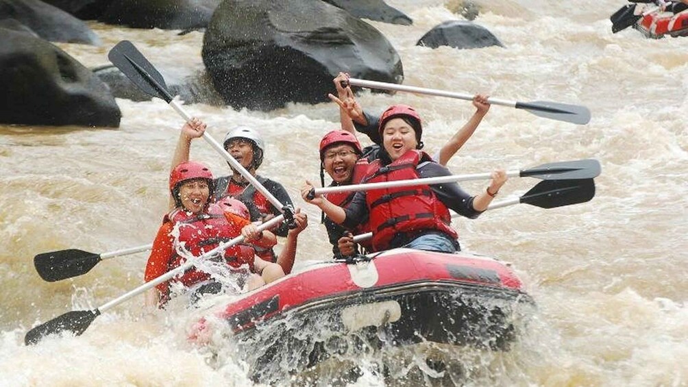 A group of people in a red raft navigating through a river with rapids. 2