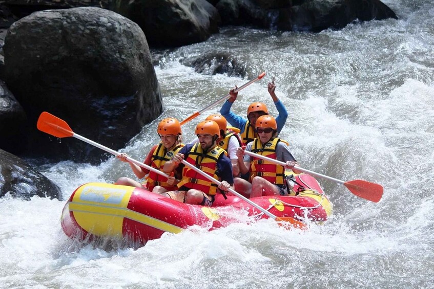 A group of people in a red and yellow raft navigating a river with rapids. 4