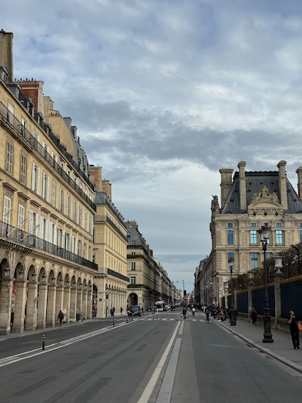 A wide street flanked by historic buildings with ornate facades and a clear sky above. 2