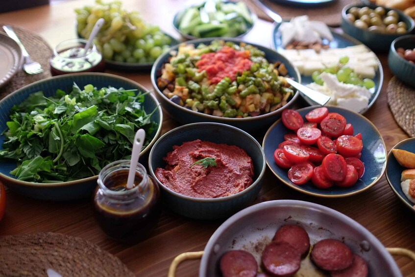 A variety of food items on a table, including greens, tomatoes, olives, and cheese. 4