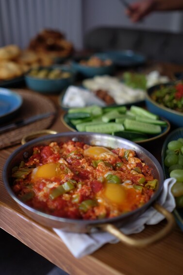 A variety of dishes including a bowl of shakshuka with eggs and vegetables, and other food items on a table. 3