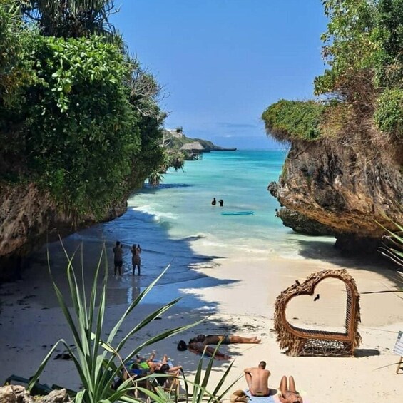 A beach with clear turquoise water, a heart-shaped seating area, and people sunbathing. 2