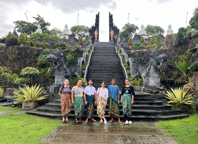 A group of people standing in front of a temple with a staircase leading to a statue. 2