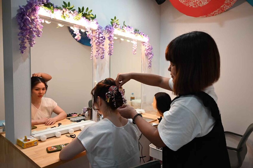 A person getting their hair styled in a salon with purple flowers and lights. 5
