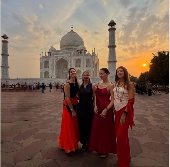 Un groupe de personnes posant devant le Taj Mahal, avec le soleil couchant en arrière-plan. 3
